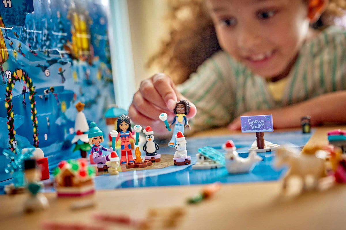 child's hand placing a small toy figure on a colorful winter-themed building set