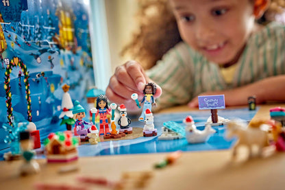 child's hand placing a small toy figure on a colorful winter-themed building set